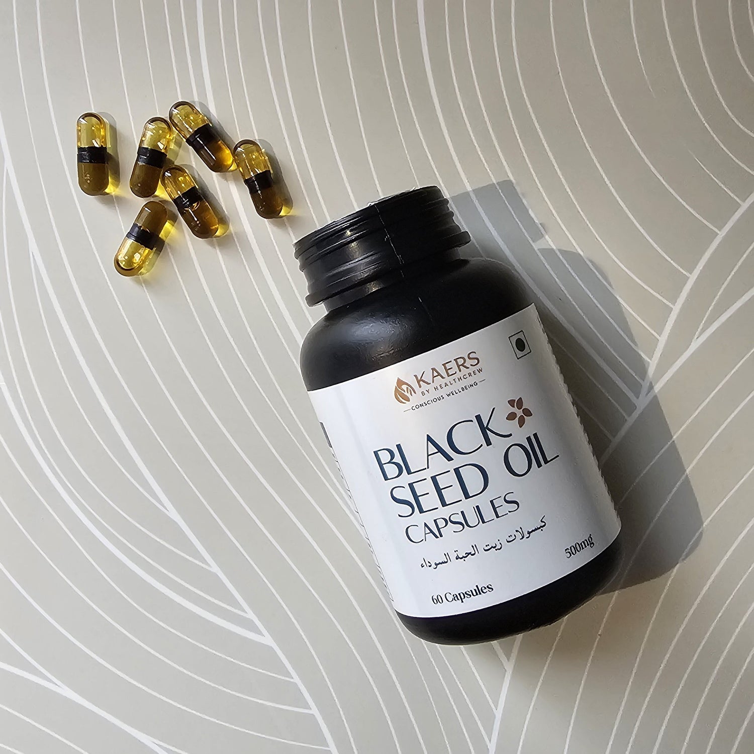 Black seed oil capsules bottle of Black Seed Organica with scattered capsules on a textured surface