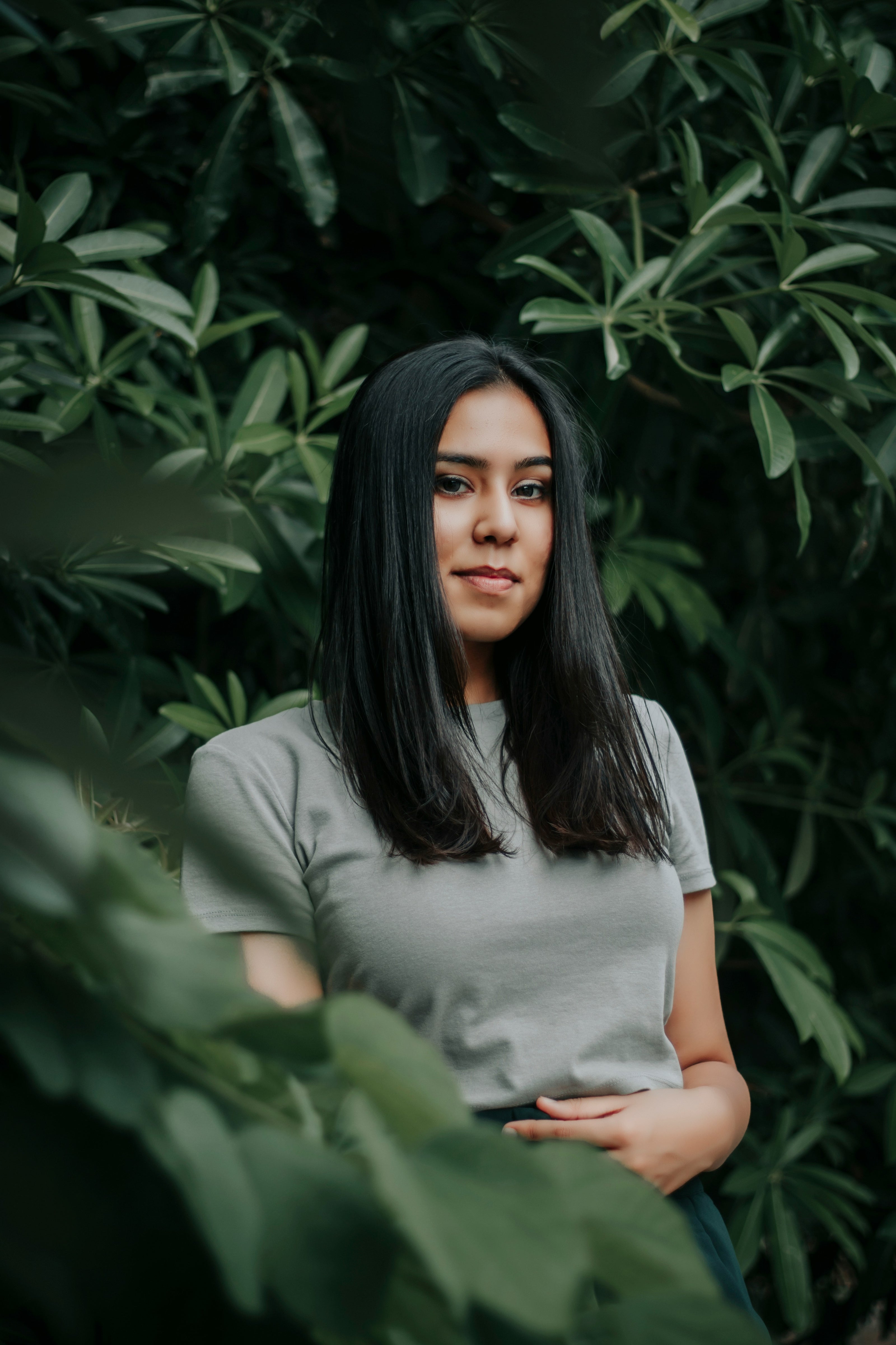 Beautiful Woman standing among green foliage